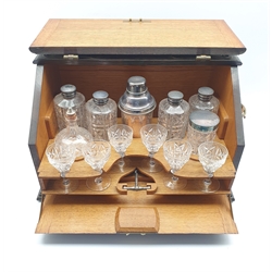 Oak table top cocktail cabinet with hinged sloping front, the interior fitted with glass spirit flasks, cocktail shaker, six Walsh cocktail glasses, corkscrew etc 49cm x 30cm x 30cm