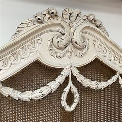 Mid-to-late 20th century French bergère 5' Kingsize bedstead, the shaped pediment carved with tied ribbon with extending foliage decorated and Vitruvian scroll frieze, mounted by bellflower festoons and turned finials, curved footboard with further festoons and trailing flowerheads, on turned feet with brass castors