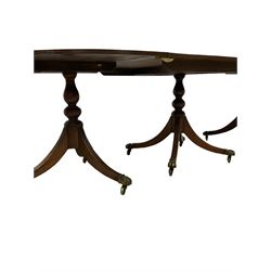 Regency design mahogany triple pillar dining table, oval top with reeded edge, over three turned vasiform pedestals with reeded sabre supports, terminating to brass hairy paw feet and castors