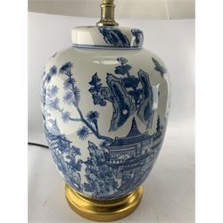 Pair of Chinese porcelain blue and white lamps in the form of ginger jars and covers, each decorated with landscape scene, raised upon gilt circular base, H63cm including shade 