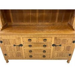 Yorkshire Oak - adzed oak dresser, raised shelves and display cabinets enclosed by glazed doors, the dresser fitted with two short and three long drawers flanked by cupboards, panelled doors and sides, wrought metal fittings 