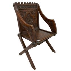 Late 19th century gothic revival oak Glastonbury chair, cresting rail carved with repeating club decoration over panelled back carved with foliate lozenge and arcade design, sloped arms and panelled seat raised on X supports