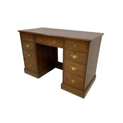 Edwardian walnut kneehole twin pedestal desk, the rectangular top with inset leather writing surface with mahogany crossbanding, central frieze drawer flanked by eight graduating drawers, raised on plinth base
