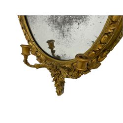 19th century gilt wood and gesso Girandole mirror, oval frame with ribbon tied pediment and extending floral decoration, the frame with foliate and egg and dart moulding, two branch candle holder over trailing laurel leaves and flower heads