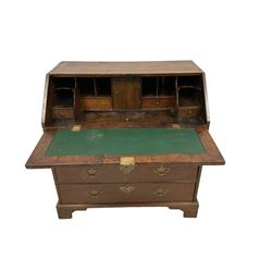 George III oak bureau, the fall-front enclosing fitted interior with inset leather writing surface, lower section with two short and two long drawers with brass handles, raised on bracket feet
