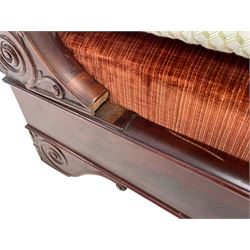 French Empire period figured mahogany lit bateau or sleigh day bed, the shaped rolled uprights decorated with applied scrolling decoration, figured frieze rail on bracket feet decorated with scrolling and carved stylised foliage, upholstered in burnt orange fabric with base and squab cushion 