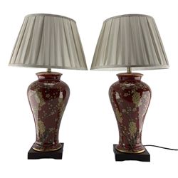 Pair of Chinese porcelain lamps, each of inverted baluster form, decorated with Jasmine blossom against a red and gilt heightened ground, raised upon a square hardwood base, H70cm including shade