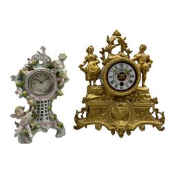 A late 19th century French gilt spelter mantle clock with an 8-day timepiece movement, decorative case with swags and standing figures of a gallant and lady in 18th century dress, with an enclosed Parisian drum movement and a coloured porcelain dial, roman numerals and a semi-circular spray of flowers, with brass hands in the gothic style. With pendulum and key. 
With a continental Sitzendorf porcelain boudoir clock depicting musical putti and encrusted rosebuds with trailing leaves, dial within a chrome bezel and  flat glass, with Arabic numerals and minute markers, 30-hour spring driven timepiece movement wound and adjusted from the rear.   
Spelter clock H28 W26 D10
Porcelain clock H23 W13 D8



