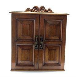 Late Victorian walnut specimen or cutlery cabinet with carved pediment, fielded panel doors each with Art Nouveau pierced brass escutcheon, four drawers with brass handles, containing various sets of silver-plated cutlery, Victorian and later, a cut glass mustard pot, foliate bread fork etc, H48cm, W38cm, D29cm