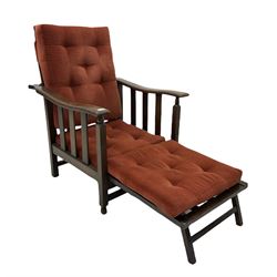 Early 20th century oak armchair, the reclining slatted back over shaped arm rests with slatted supports, fold over integral foot rest, with squab cushions upholstered in buttoned velvet, all raised on block and turned supports united by stretchers W70cm