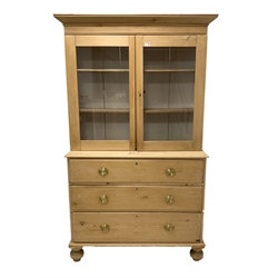Victorian polished pine cabinet on chest, projecting cornice over two glazed doors enclosing interior fitted with two shelves, three long drawers under, raised on turned supports 