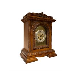German - early 20th century 8-day chiming mantle clock in a carved oak case, chiming the hours and quarters on 5 gong rods, brass dial with a silver chapter ring and Arabic numerals. with key and pendulum.