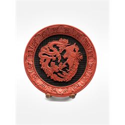 20th century Chinese Cinnabar style plate, centrally decorated with a Dragon and Phoenix within foliate border, on stand D28.5cm