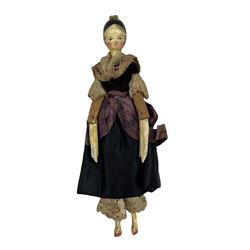19th century painted wood peg doll, with carved and painted features, painted black hair with curls and tuck comb, peg jointed at the shoulders, elbows, hips and knees, painted white lower legs and arms, red slippers, original purple dress with point lace detail, L16cm 