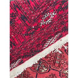 Persian Bokhara red ground rug, the field decorated with three rows of Gul motifs, multiple band border decorated with stylised motifs and geometric patterns