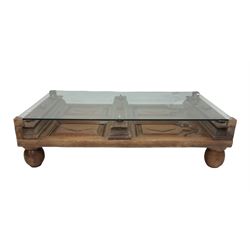 Indian hardwood coffee table, the raised glass panel over carved base with panels and lozenges, raised on turned supports 