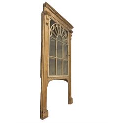 Early 20th century pine corner cabinet, the projecting cornice over a fluted frieze, fitted with astragal glazed door with swag decoration enclosing two shelves, the door flanked by fluted column uprights, the rear support terminating in spade foot 