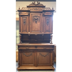 Early 20th century carved oak buffet, raised back with three cupboards supported by turned tapered and reeded uprights, two drawers and two cupboards under, raised on compressed bun supports 