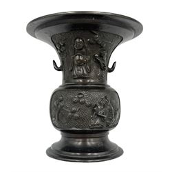 Chinese bronze gu vase decorated with a raised pattern of flowering branches, figures holding book, scrolls and fan on a circular foot H13cm