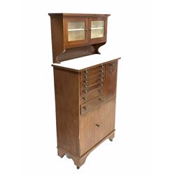 Edwardian mahogany dentists cabinet, the raised back with two bevel glazed doors each enclosing a shelf, over one bank of seven graduated drawers, another drawer, fall front cupboard and double cupboard to base, raised on castors H158cm