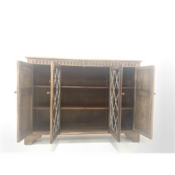 Reprodux oak cupboard bookcase, with lunette carved frieze over lead glazed door to centre and two cupboards, each enclosing two shelves, W135cm, H100cm, D29cm