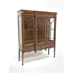 Edwardian mahogany break front display cabinet, satinwood crossbanded and boxwood and ebonised string inlay to frieze over three tracery glazed doors enclosing velvet lined interior and single fixed shelf, three drawers under, shaped apron, raised on square tapered supports with peg feet, W127cm, H157cm, D41cm