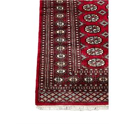 Persian Tekke Bokhara red ground rug, the field decorated with four rows of repeating Gul motifs, multi-band border with geometric design (244cm x 153cm); and a similar runner (188cm x 64cm)