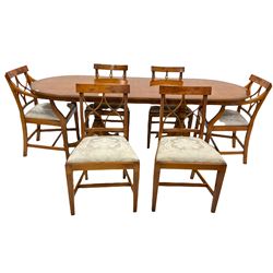 Bevan funnel Reprodux Regency style yew wood twin pillar dining table, the oval cross banded top with one additional leaf stored to centre, raised on turned columns leading to triple splay supports with brass cup castors, (218cm x 89cm, H77cm) together with a set of 6 (4+2) Reprodux dining chairs with drop in upholstered seat pads, raised on square tapered and reeded supports 
