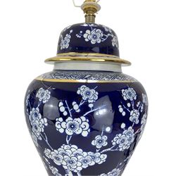 Pair of blue and white table lamps, each in the form of a vase and cover, decorated with cherry blossom, within foliate and geometric borders, raised upon circular gilt bases, H48cm excluding fitting