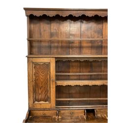 18th century design oak dresser, the boarded plate rack with fretwork frieze rail over two shelves and two cupboards, inverted breakfront base with raised back fitted with small drawers, moulded top over applied fretwork decoration and a bank of five central drawers flanked by quarter columns, two long drawers and two cupboards below, the cupboards enclosed by fielded panel doors, on bun feet

Reputed to have been made by John Tomlinson of Appleton le Moors for the Dobson family 