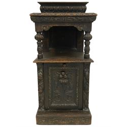 19th century Jacobean Revival heavily carved oak purdonium, raised back carved with acanthus leaves, the moulded and carved edge supported by turned baluster columns uniting the under-tier, the fall-front heavily carved with a floral design flanked by fruit moulded uprights