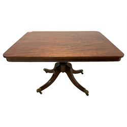 George III mahogany breakfast table, rectangular tilt-top with rounded corners, on turned columns with quadruple splayed supports with brass cups and castors