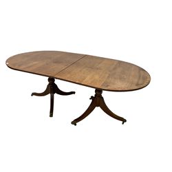 Regency design mahogany twin pedestal dining table, oval top with crossbanding and boxwood stringing, with reeded edge, raised on turned pedestals with tripod base, the splayed supports terminating in brass hairy paw feet and castors, with additional leaf