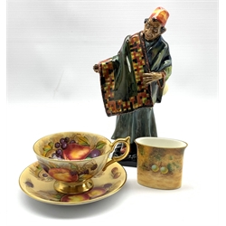 Royal Worcester porcelain oval cigarette holder hand painted with fruit together with an Aynsley teacup and saucer with printed fruit decoration, signed N Brunt and a Royal Doulton Figure 'The Carpet Seller'(3)
