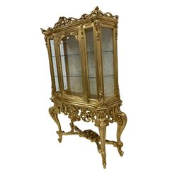 Silik Lo Stile Di Classe - Italian Rococo style carved gilt display cabinet, pierced scrolling pediment with central cartouche, fitted with single glazed door, ornate carved apron with pierced foliate and scrolled moulding, shell and flower head motifs, raised on cabriole supports united by cross stretcher