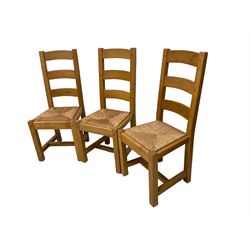 Solid light oak rectangular extendable dining table, fitted with single drawer and raised on square supports, with two additional leaves (W150 D85 H78); and four ladder back dining chairs with rush seats (W47 D43 H104)
