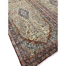 Persian double Kerman ivory ground carpet, the busy field decorated with trailing branches and stylised plant motifs, indigo ground central medallion with floral design, the border decorated with repeating flower head and foliage pattern, with guard stripes