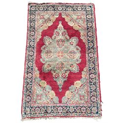 Small Persian red ground rug, the plain field with floral design medallion and spandrels, triple band border decorated with stylised flower head motifs