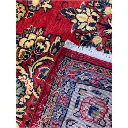 Persian Kerman crimson ground rug, the central floral lozenge surrounded by bouquets of flowers with golden outlines, the matching spandrels with additional leaf motifs, the gold border with repeating stylised palmettes united by scrolling branches