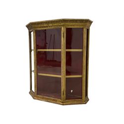 Late 19th century gilt framed wall display cabinet, the projecting cornice moulded with egg and dart decoration, fitted with five glazed panels and a central door, enclosing two gilt shelves