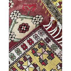 Turkish crimson ground rug, the field with four central lozenges with foliate and flower head decoration, the guarded border with wide yellow band decorated with repeating geometric motifs, outer ivory guard with flower heads