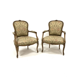 Pair of French style beech upholstered open salon armchairs, floral carved cresting rail, incised and scroll carved arm terminals, raised on carved cabriole supports, W64cm