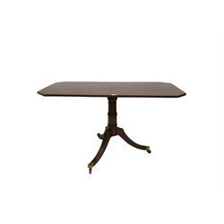 Regency style mahogany tilt-top table, canted rectangular top on collar turned column, three splayed supports with brass cups and castors