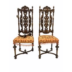 Pair of Victorian oak high back hall chairs, the back profusely carved with scrolls and foliate, upholstered seats, raised on turned supports united by 'X' stretcher W47cm