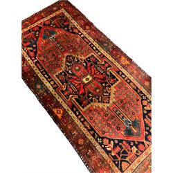Persian indigo ground rug, the central geometric medallion within a red field surrounded by interconnected geometric flowerheads, the indigo spandrels filled with stylised plant motifs, the guarded border decorated with repeating patterns