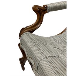 19th century carved walnut low open armchair, scrolled back and curved seat upholstered in contemporary striped buttoned fabric, the arms on carved shaped supports with foliage decoration, scroll carved cabriole front feet terminating at brass castors