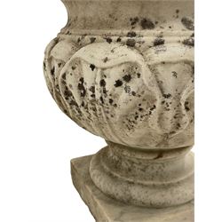 Pair of 19th century weathered white marble urns, the body with carved stylised foliage decoration, on moulded foot and square base 