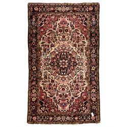 Persian ground rug, pale ground field with central medallion surrounded by trailing floral design and urns to each end, the border and spandrels decorated with flower head motifs