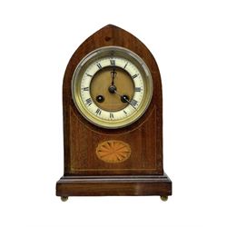 An Edwardian mahogany veneered Lancet cased mantle clock with oval inlay and stringing, on a moulded plinth raised on four bun feet, eight-day French rack striking movement, striking the hours and half hours on a coiled gong, two-part dial with a gilt centre, enamel chapter ring with roman numerals and minute markers, steel fleur di lis hands within a beaded cast bezel with a flat bevelled glass. With Pendulum


