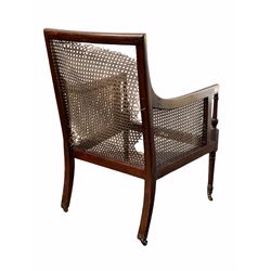 Early 20th century Regency design mahogany elbow chair, with bergere back and side panels, raised on turned front supports with castors, bearing ivorine label for 'Gullachsen & Son Ltd' W61cm